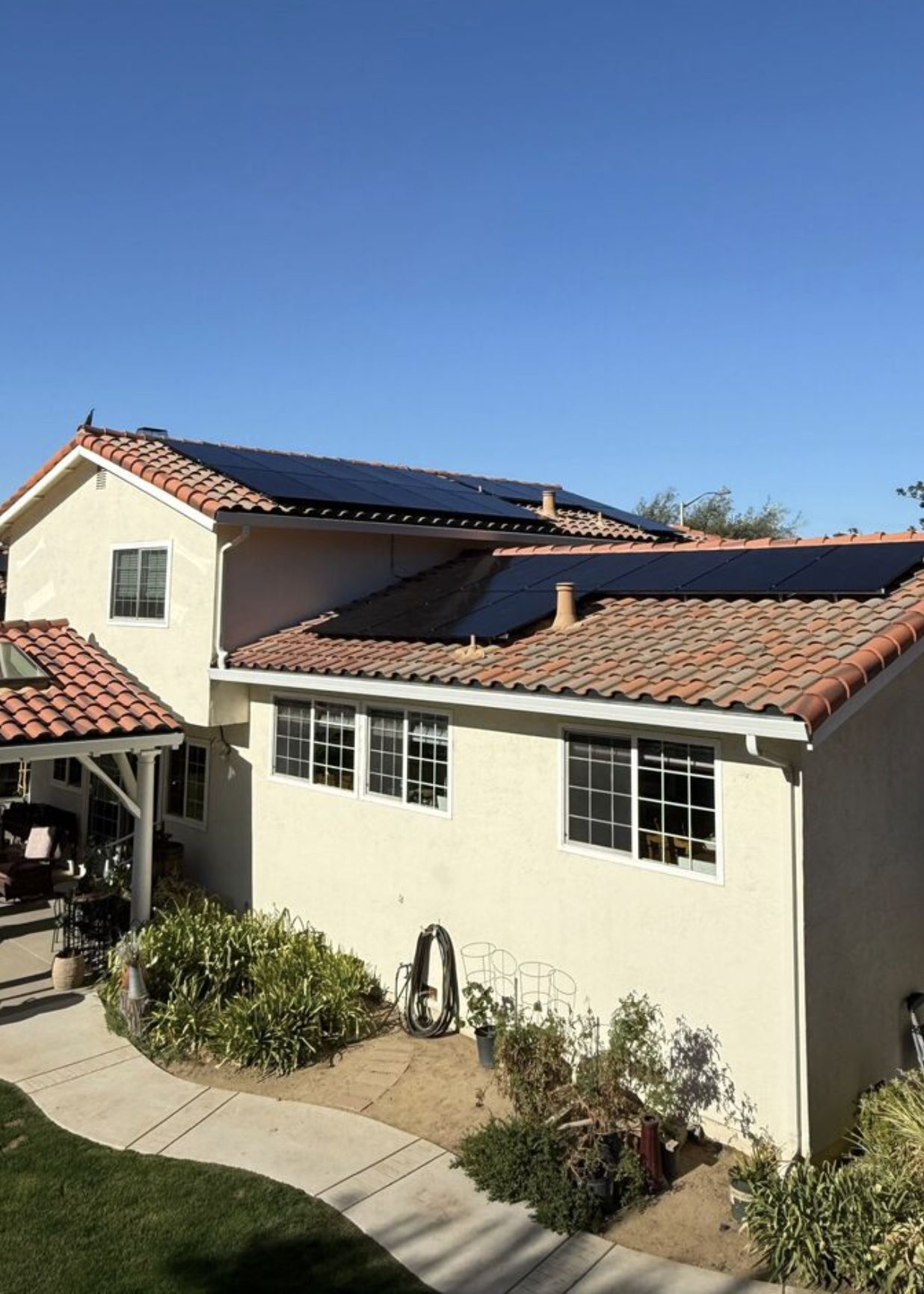 Spanish tile roof solar installation — stucco home, blue sky