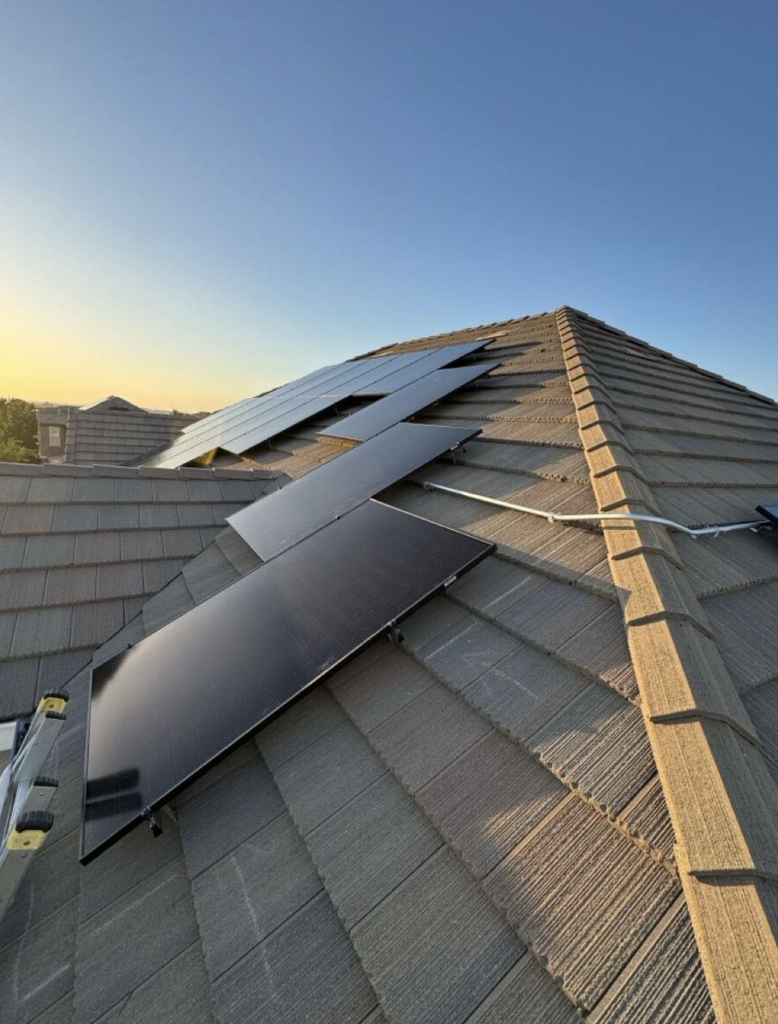 Sunset solar panel installation — panels mid-install on tile roof
